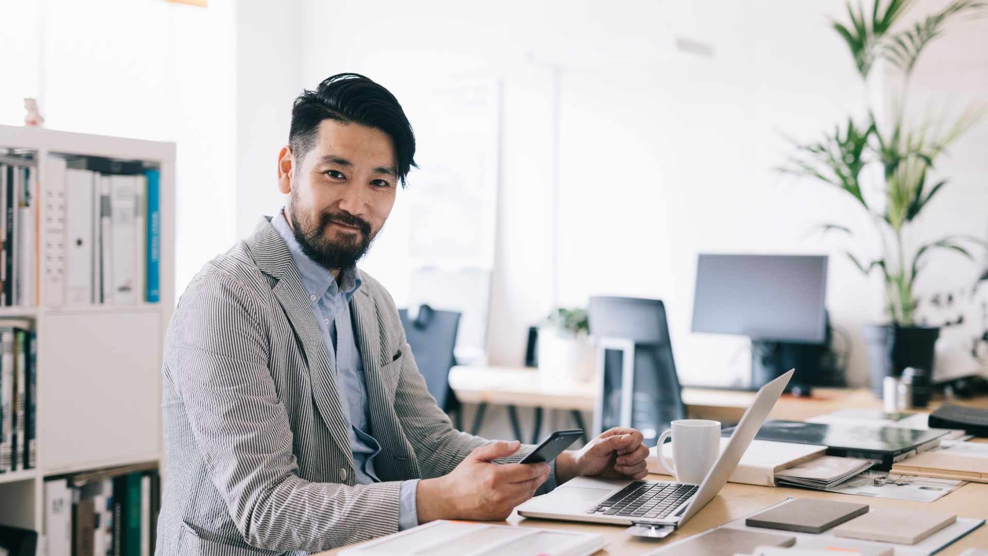 Asian business owner using technology at his desk.